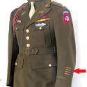 Que signifie la ou les barrette(s) cousue(s) sous le patch d'épaule, en bas de la manche gauche de la veste de sortie ?